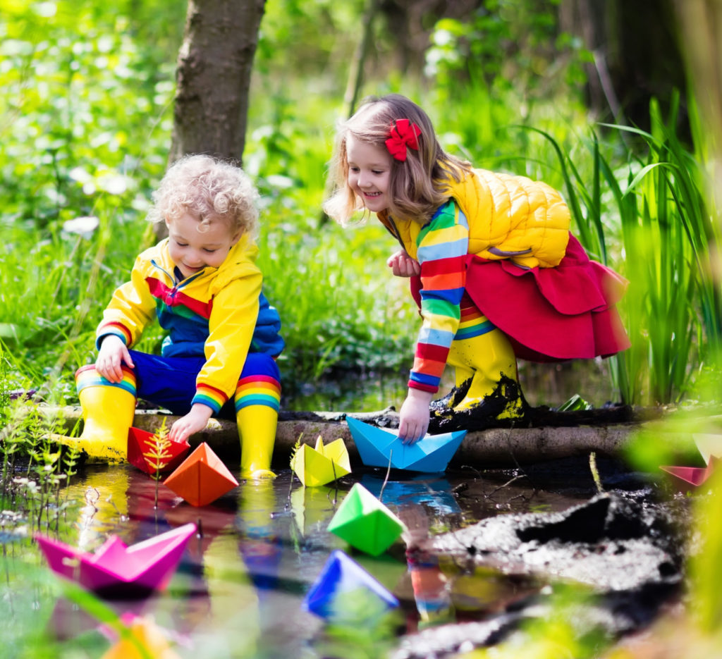 Children,Play,With,Colorful,Paper,Boats,In,A,Small,River